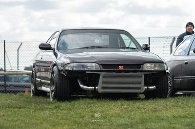 Grey sedan parked to the right of the Nissan Skyline.